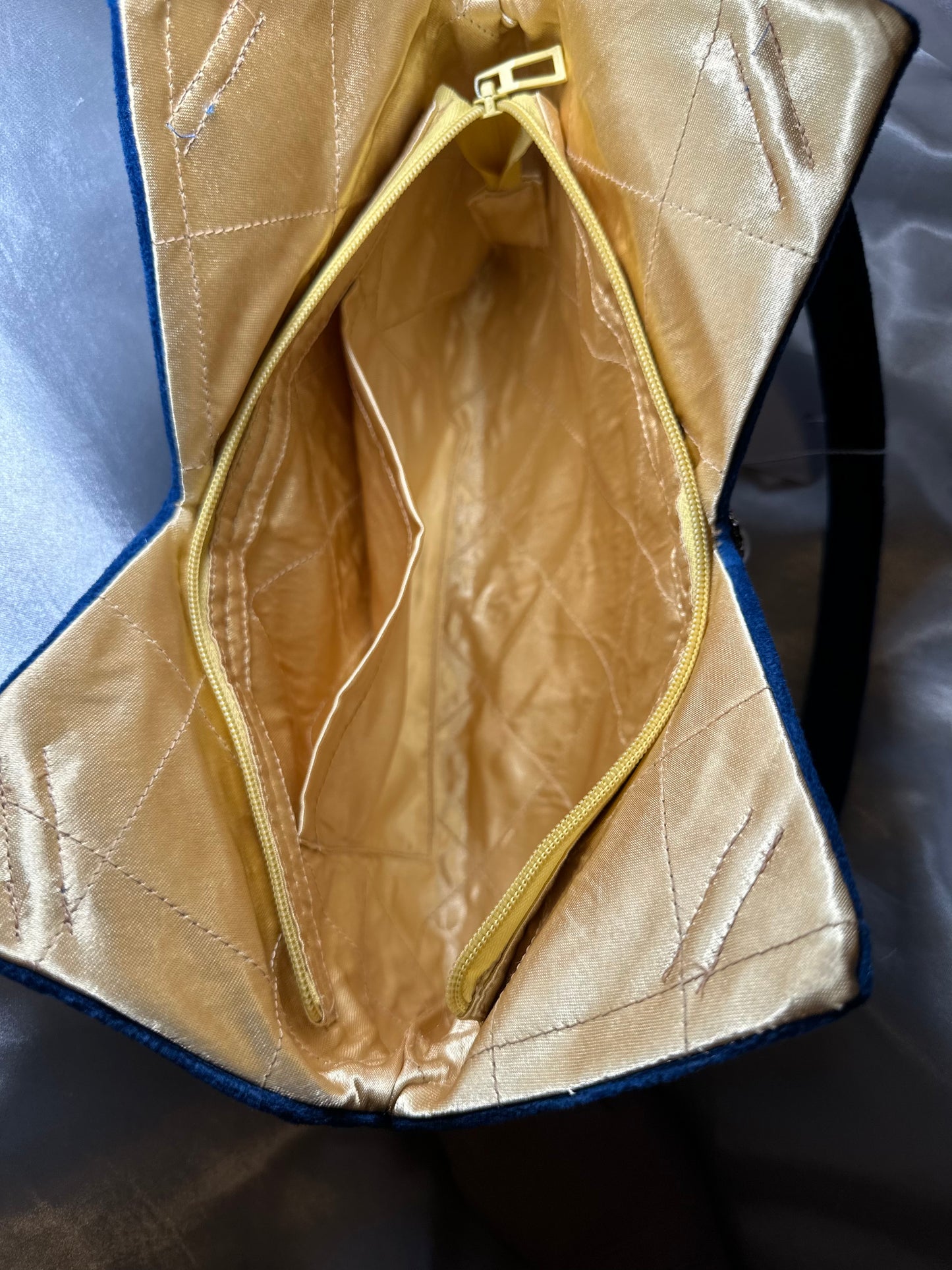 close up image of inner lining ,zipper, and 1 open pocket for small items. inside lining material is made of charmeuse satin.